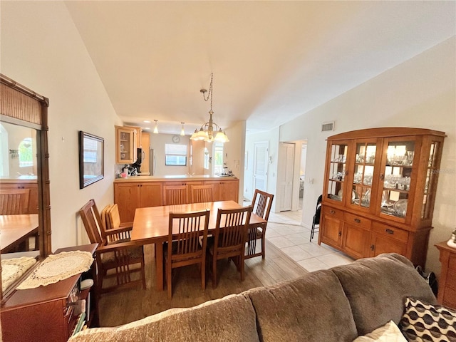 dining room with light tile patterned floors, vaulted ceiling, and a notable chandelier