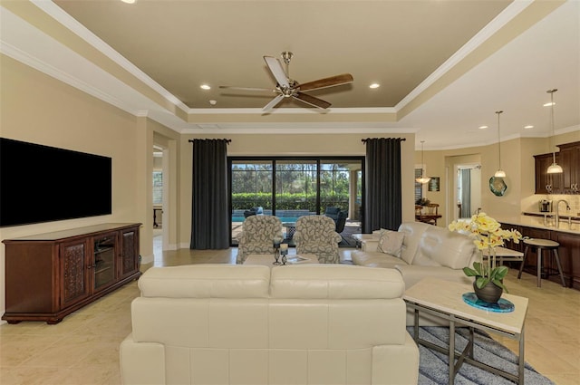 tiled living room with ceiling fan, a raised ceiling, ornamental molding, and sink