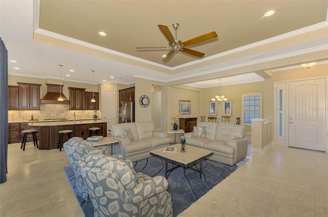 tiled living room featuring a raised ceiling, crown molding, sink, and ceiling fan with notable chandelier