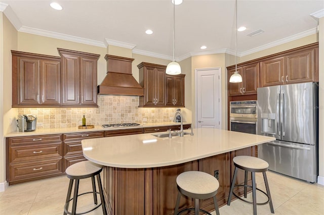 kitchen with a center island with sink, crown molding, decorative light fixtures, custom range hood, and stainless steel appliances