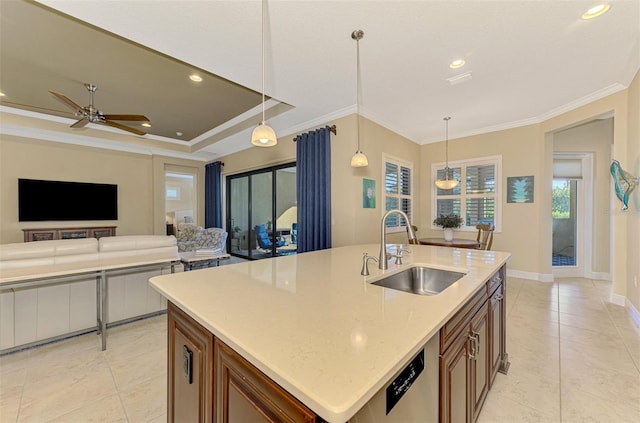 kitchen featuring pendant lighting, crown molding, sink, and a kitchen island with sink