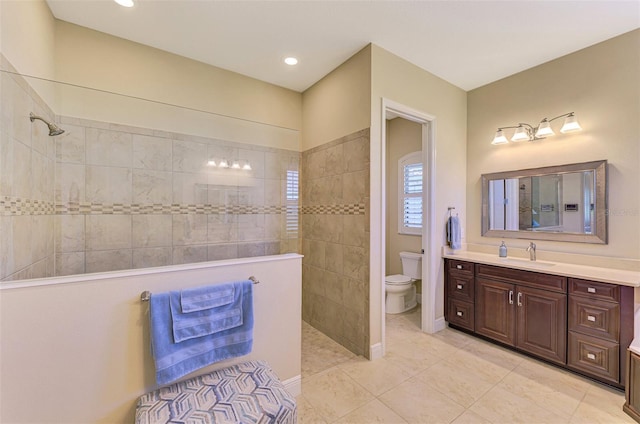 bathroom featuring a tile shower, tile patterned flooring, vanity, and toilet