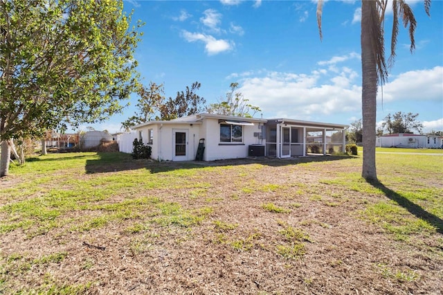 view of front of home with a front yard, central air condition unit, and a sunroom