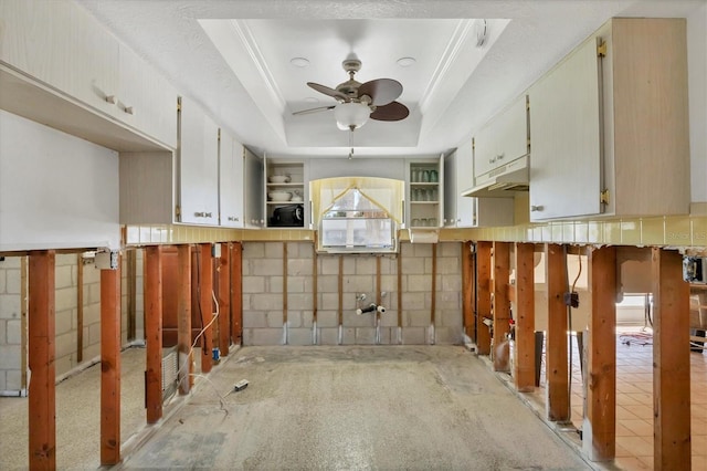 kitchen with white cabinets, a raised ceiling, crown molding, ceiling fan, and carpet floors