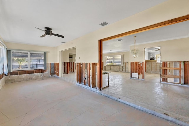 empty room featuring ceiling fan with notable chandelier, plenty of natural light, and ornamental molding