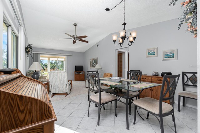 tiled dining area with ceiling fan with notable chandelier, a textured ceiling, and vaulted ceiling