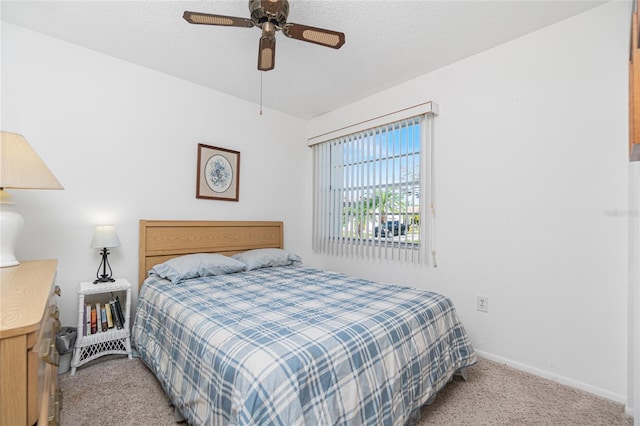 bedroom featuring ceiling fan, light colored carpet, and a textured ceiling