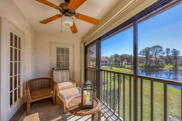 sunroom / solarium featuring ceiling fan and a water view