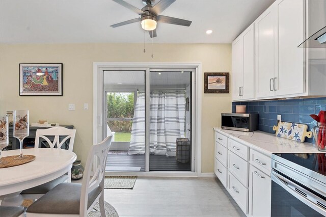 kitchen featuring decorative backsplash, light stone counters, white cabinets, and appliances with stainless steel finishes