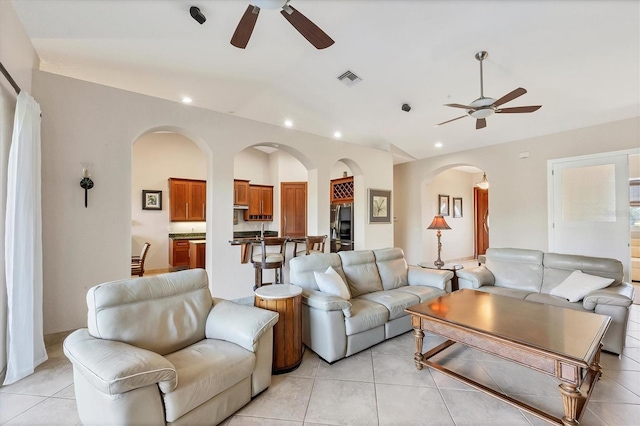 living room with ceiling fan, light tile patterned floors, and vaulted ceiling