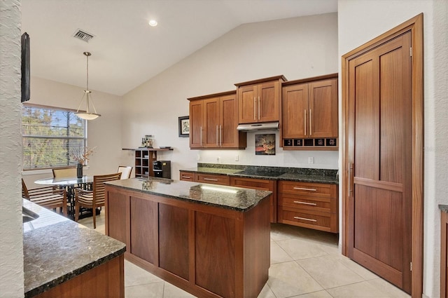 kitchen with light tile patterned floors, a center island with sink, vaulted ceiling, and hanging light fixtures