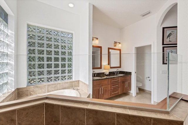 bathroom featuring vanity, a healthy amount of sunlight, toilet, and tiled tub