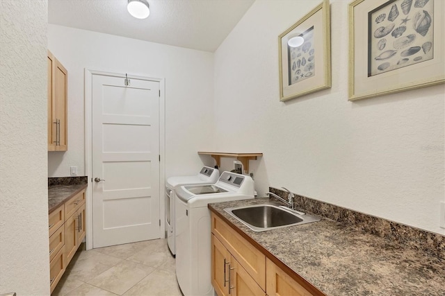 clothes washing area featuring cabinets, a textured ceiling, sink, washing machine and dryer, and light tile patterned flooring