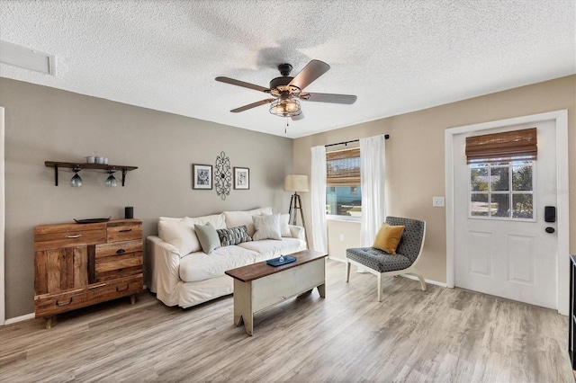 living room featuring ceiling fan, a textured ceiling, and light hardwood / wood-style flooring