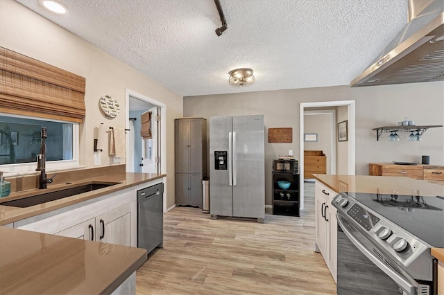 kitchen featuring sink, light wood-type flooring, a textured ceiling, white cabinetry, and stainless steel appliances