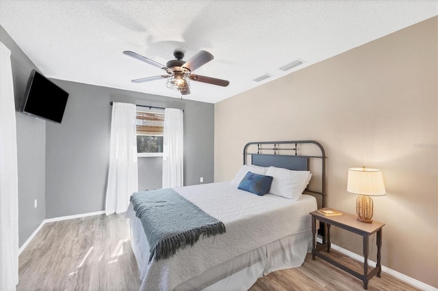 bedroom featuring a textured ceiling, light hardwood / wood-style floors, and ceiling fan