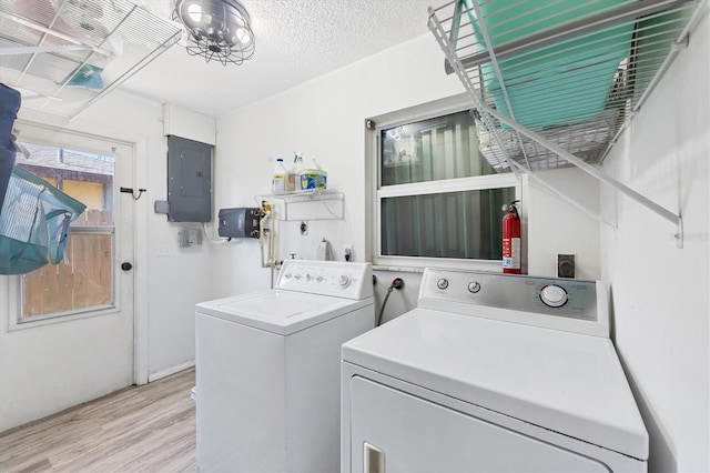 washroom with electric panel, an inviting chandelier, washing machine and dryer, a textured ceiling, and light hardwood / wood-style floors