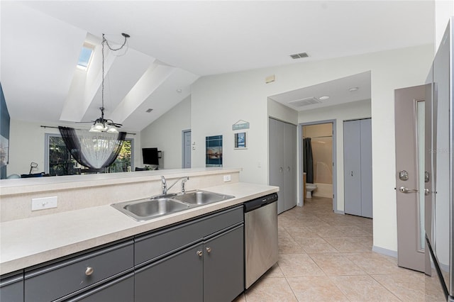 kitchen featuring sink, stainless steel dishwasher, gray cabinets, vaulted ceiling with skylight, and light tile patterned floors