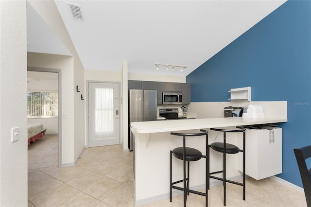 kitchen featuring gray cabinetry, a breakfast bar, light tile patterned flooring, kitchen peninsula, and stainless steel appliances