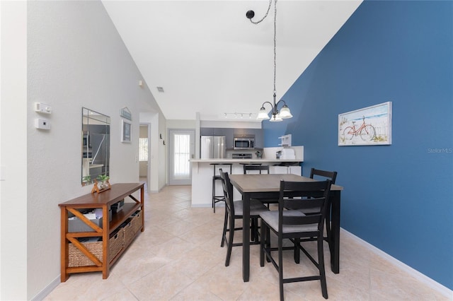 tiled dining space featuring high vaulted ceiling and an inviting chandelier