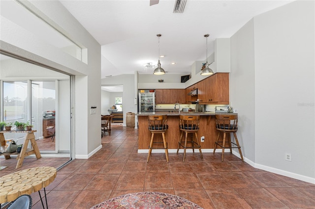 kitchen featuring kitchen peninsula, vaulted ceiling, a wealth of natural light, and hanging light fixtures