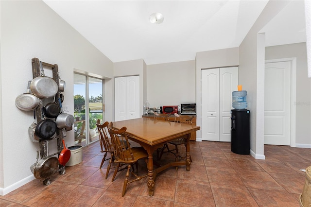 dining space featuring dark tile patterned flooring and lofted ceiling