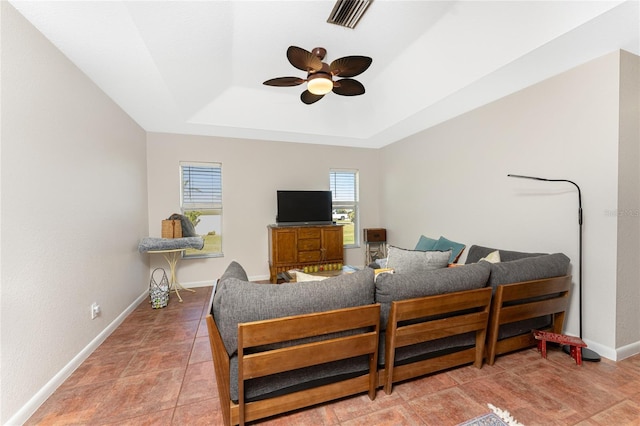 living room with a tray ceiling and ceiling fan