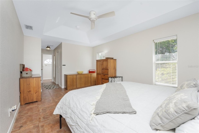 bedroom featuring light tile patterned floors, a tray ceiling, and ceiling fan