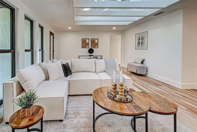 living room featuring light wood-type flooring and a skylight