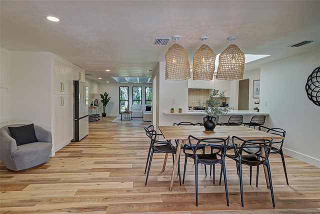 dining area with a skylight and light hardwood / wood-style floors