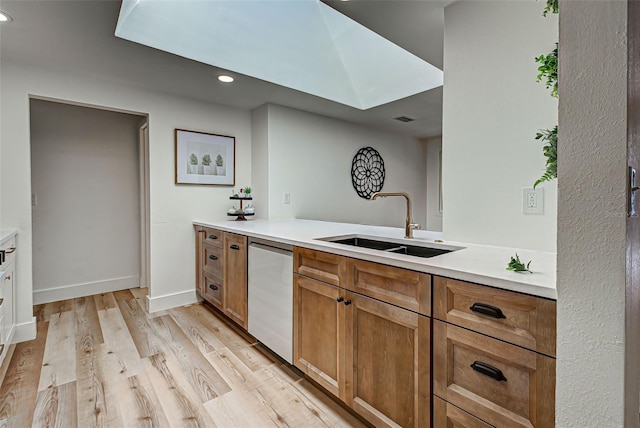 kitchen with dishwasher, sink, and light wood-type flooring