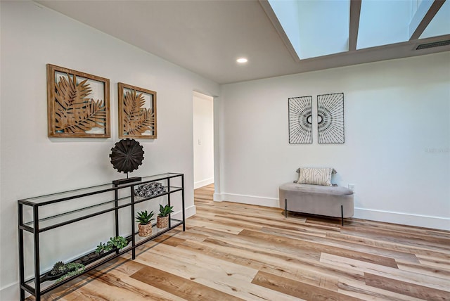 living area with a skylight and light hardwood / wood-style flooring