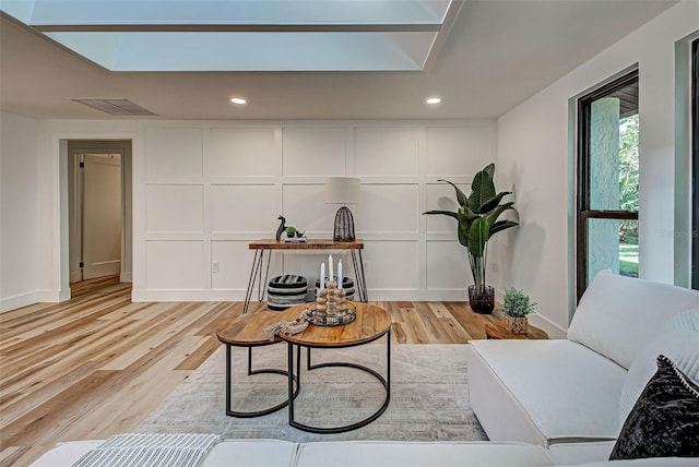 living room featuring light wood-type flooring and a skylight