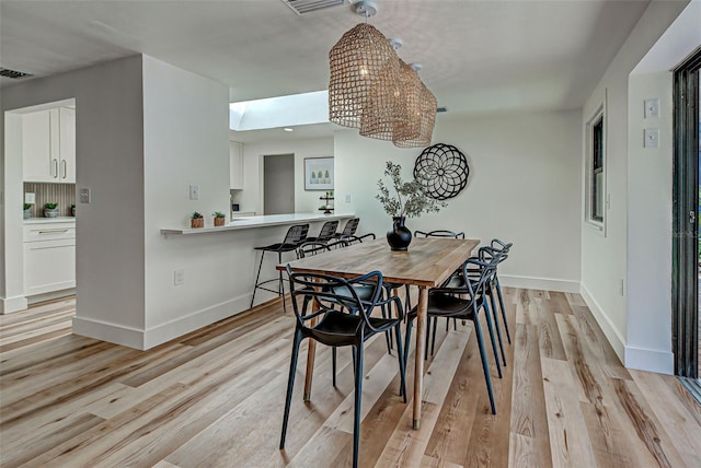 dining area with light hardwood / wood-style flooring and a skylight