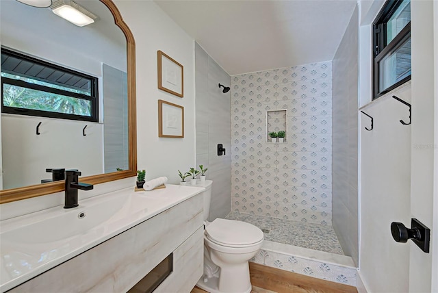 bathroom featuring tiled shower, hardwood / wood-style floors, vanity, and toilet