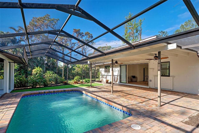 view of swimming pool featuring glass enclosure, ceiling fan, and a patio area