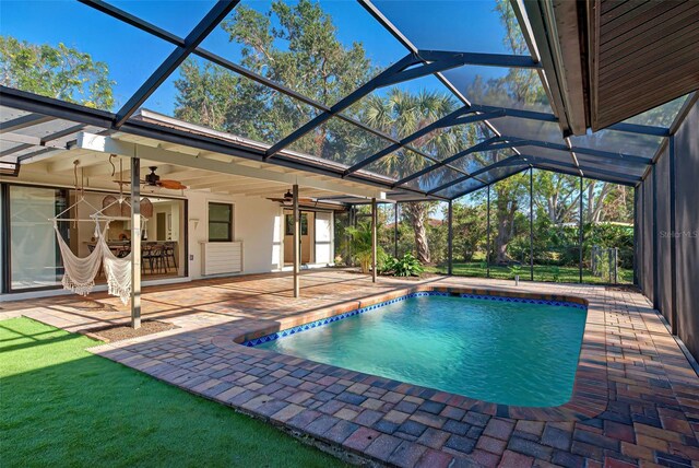 view of pool with glass enclosure, ceiling fan, and a patio