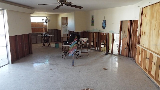 misc room with ceiling fan with notable chandelier and wood walls