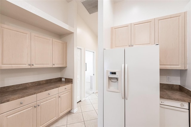 kitchen with lofted ceiling, light tile patterned flooring, and white appliances