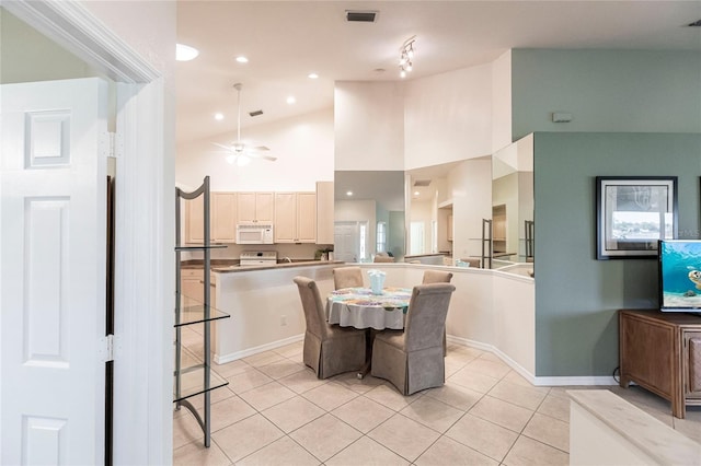 dining room with ceiling fan, high vaulted ceiling, and light tile patterned flooring