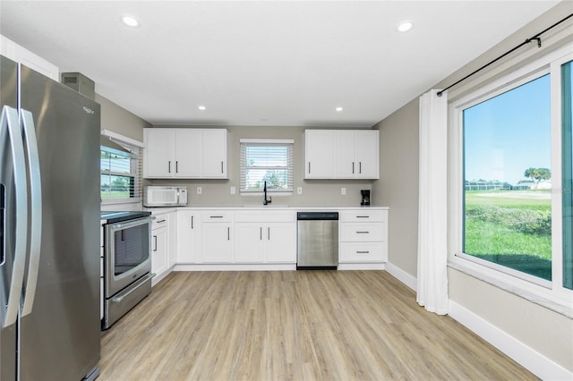 kitchen featuring appliances with stainless steel finishes, light hardwood / wood-style floors, white cabinetry, and sink