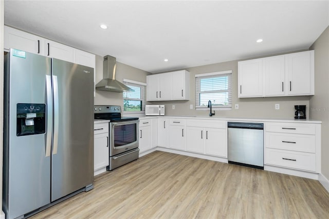 kitchen featuring appliances with stainless steel finishes, white cabinetry, plenty of natural light, and wall chimney exhaust hood