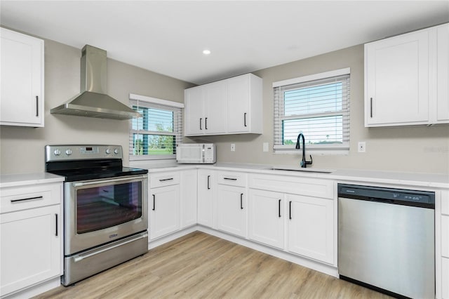 kitchen featuring stainless steel appliances, a wealth of natural light, wall chimney exhaust hood, and sink