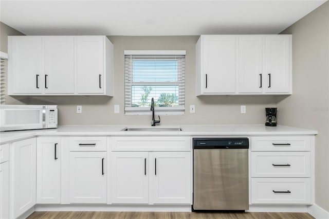 kitchen with dishwasher, white cabinets, light hardwood / wood-style floors, and sink