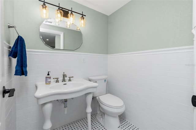 bathroom featuring tile patterned floors, sink, toilet, and tile walls