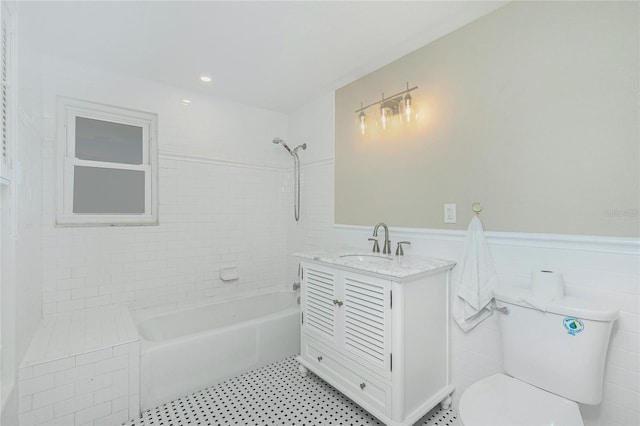 full bathroom featuring vanity, toilet, tile walls, and tiled shower / bath combo