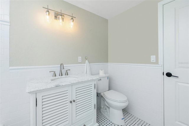 bathroom featuring tile patterned floors, vanity, toilet, and tile walls