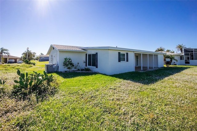 rear view of property with central AC and a yard