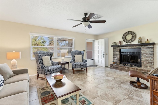 tiled living room with a textured ceiling, ceiling fan, and a fireplace