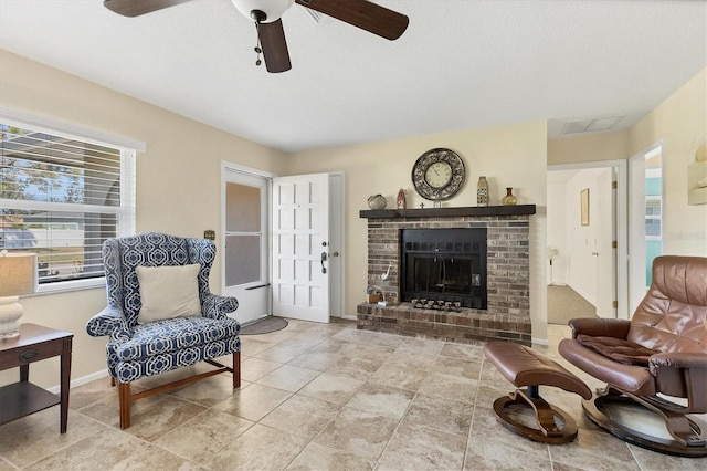 living room featuring ceiling fan and a brick fireplace